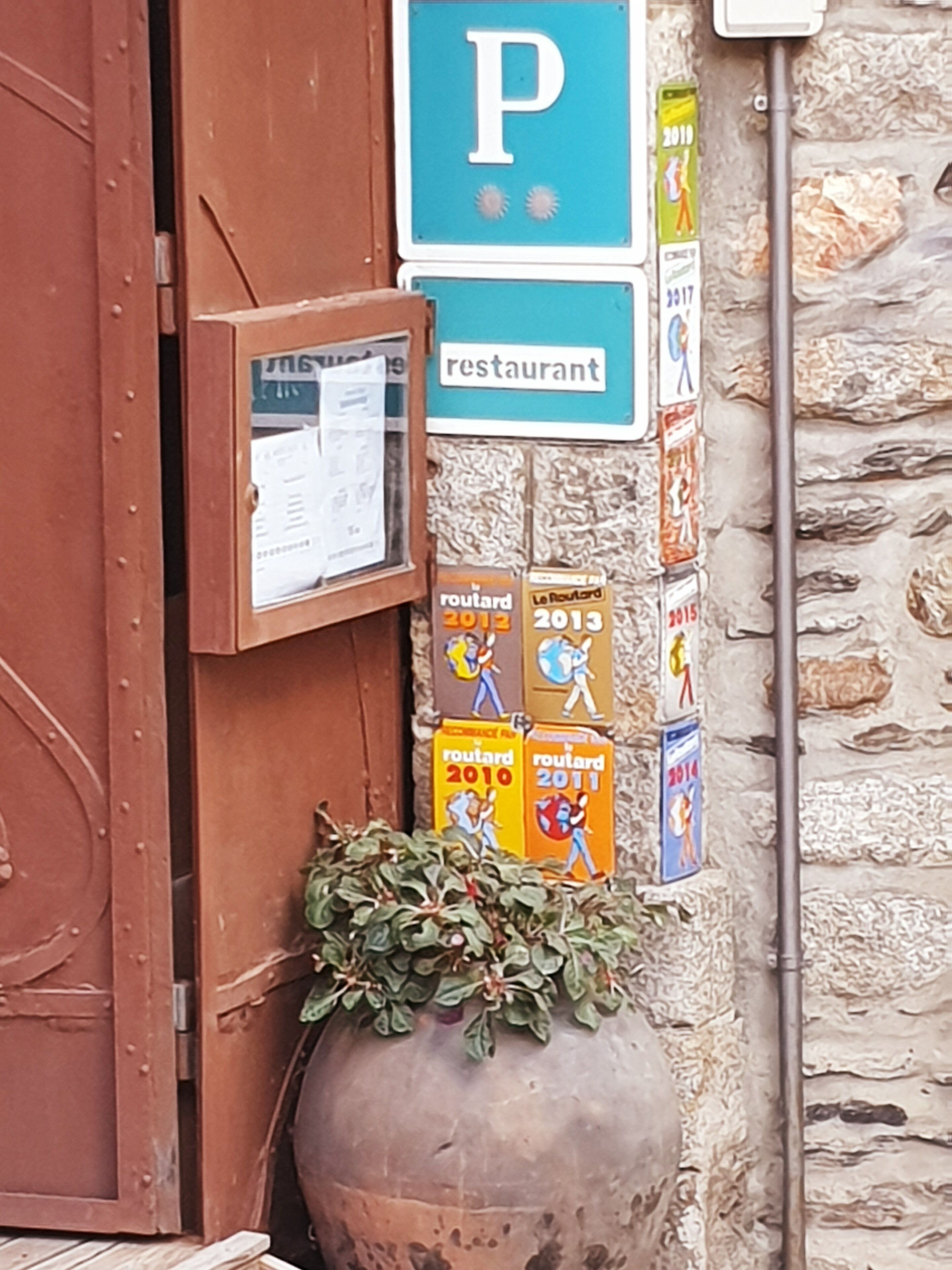 A building entrance with a 'P' parking sign, a restaurant sign, and multiple 'Route 2010' to '2015' event posters.