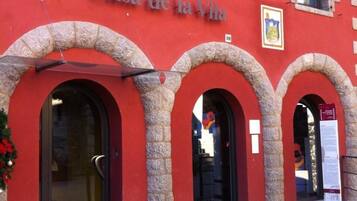 Un edificio rojo con arcos de piedra y el cartel "Casa de la Vila" sobre la entrada.