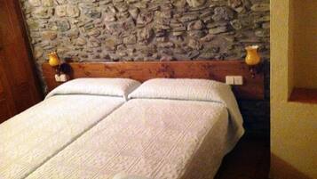 A double bed with a stone wall behind it and two bedside lamps.