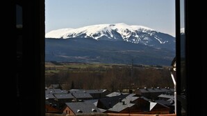 A view of a snow-capped mountain with a residential area in the foreground. - Hostal Ruso (Llívia)