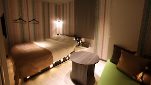 Une chambre d’hôtel moderne avec un grand lit, une table de chevet et une petite table ronde.