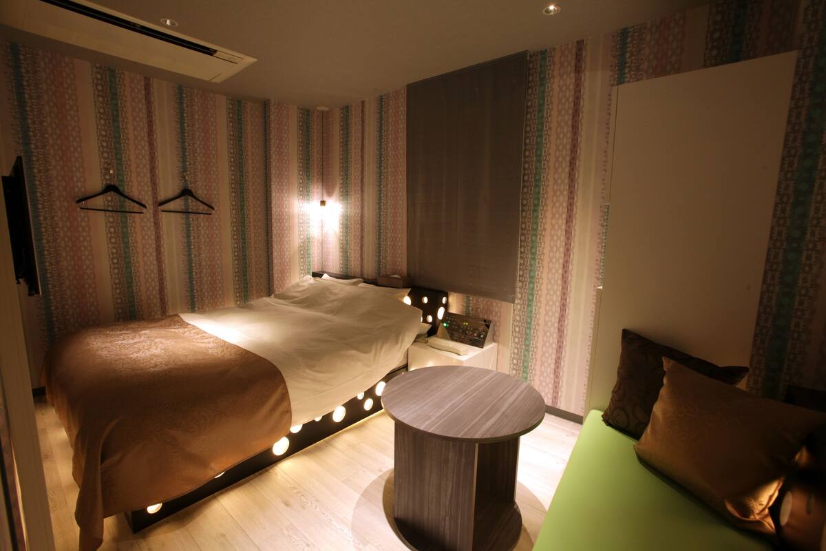 Een moderne hotelkamer met een groot bed, nachtkastje en een klein rond tafeltje.