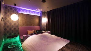 Une chambre d’hôtel avec un lit, une petite table, un panneau de commande fixé au mur et un mur décoré d’un motif.