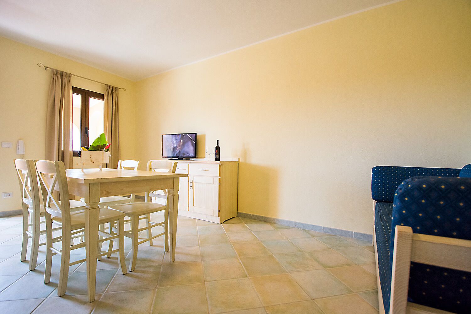 Un comedor con una mesa y sillas de madera, un televisor y un armario.