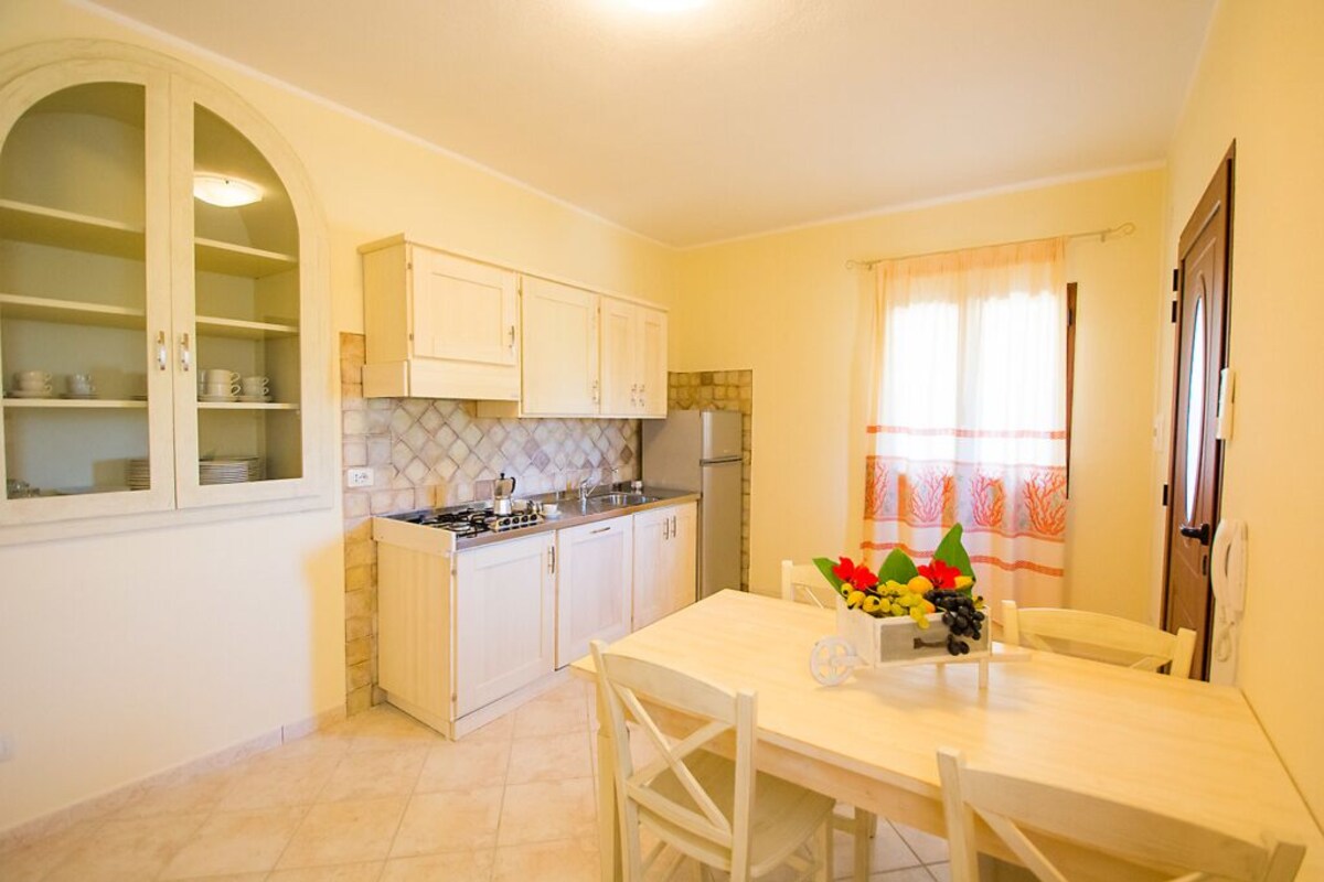 Une cuisine avec des meubles blancs, une cuisinière à gaz et une table à manger avec des chaises.