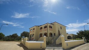 A two-story building with a beige facade, multiple balconies, and a gated entrance. - Le Residenze del Maria Rosaria - Vico Friuli 1 (Orosei)