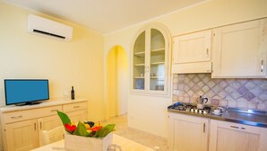 A kitchen with a stove, cabinets, and a TV on a counter. - Le Residenze del Maria Rosaria - Vico Friuli 1 (Orosei)