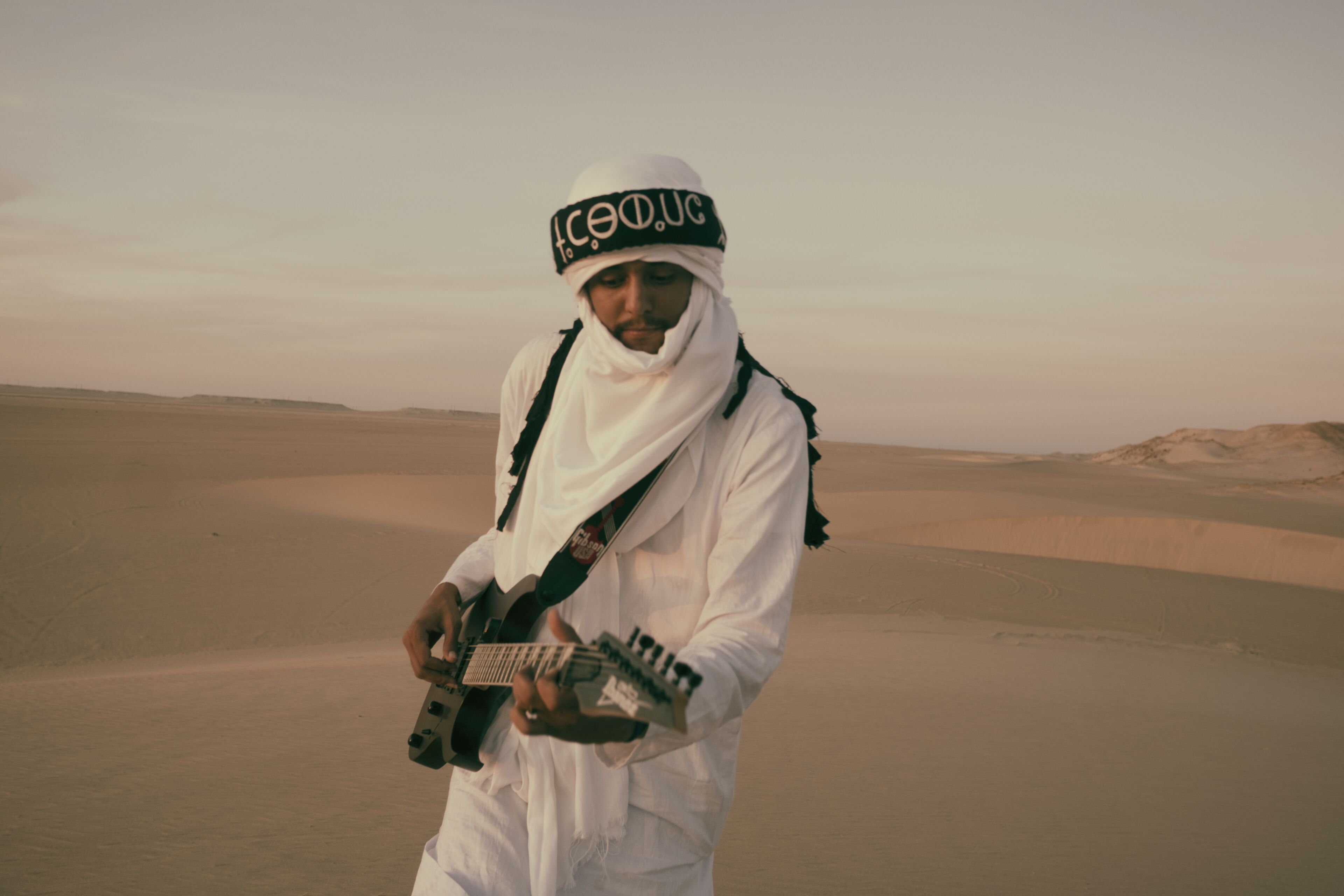 A person in a desert landscape with sand dunes in the background.