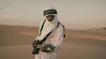 A person in a desert landscape with sand dunes in the background.