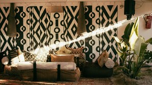 A cozy living room with a patterned wall, a sofa with cushions, a hanging light fixture, and a plant. - Les Dunes de Dakhla (Dakhla)