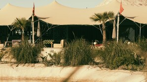 A desert resort with tents, palm trees, and a body of water. - Les Dunes de Dakhla (Dakhla)
