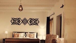 A bedroom with a bed, a chair, a rug, a wall decoration, and a hanging light fixture. - Les Dunes de Dakhla (Dakhla)
