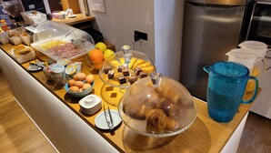 Una mesa de buffet con diferentes alimentos, como frutas, huevos y postres, en un entorno de hotel.