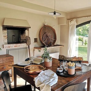 A rustic dining area with a brick oven, a large woven basket, and a view of the outdoors. - Casale Valigi (Narni)