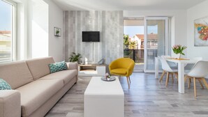 A modern living room with a sofa, coffee table, and a yellow armchair. There is a flat-screen TV mounted on the wall and a dining area with a table and chairs. - Villa Cindric (Medulin)