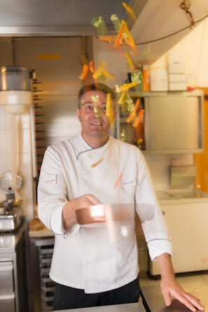 A chef in a professional kitchen with stainless steel appliances and a clean, organized layout. - Appartements-Restaurant Schwaiger (Bad Mitterndorf)