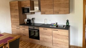 Una cocina compacta con armarios de madera, un microondas, una estufa y un lavabo.
