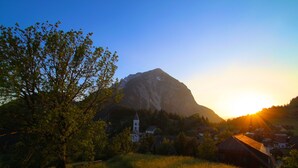 A mountainous landscape with a church and residential buildings during sunset.