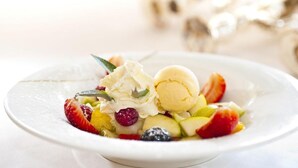 A dessert plate with ice cream and assorted fruits.