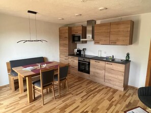 A compact kitchen with wooden cabinets, a microwave, and a built-in oven.