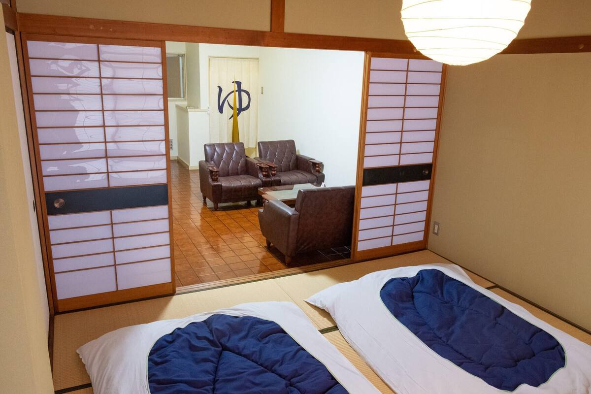 A traditional Japanese room with tatami flooring, a shoji screen, and a futon bed.