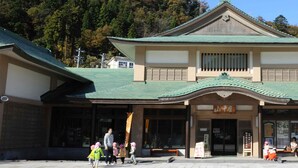 Un edifici japonès tradicional amb un teulat corbat i un cartell.