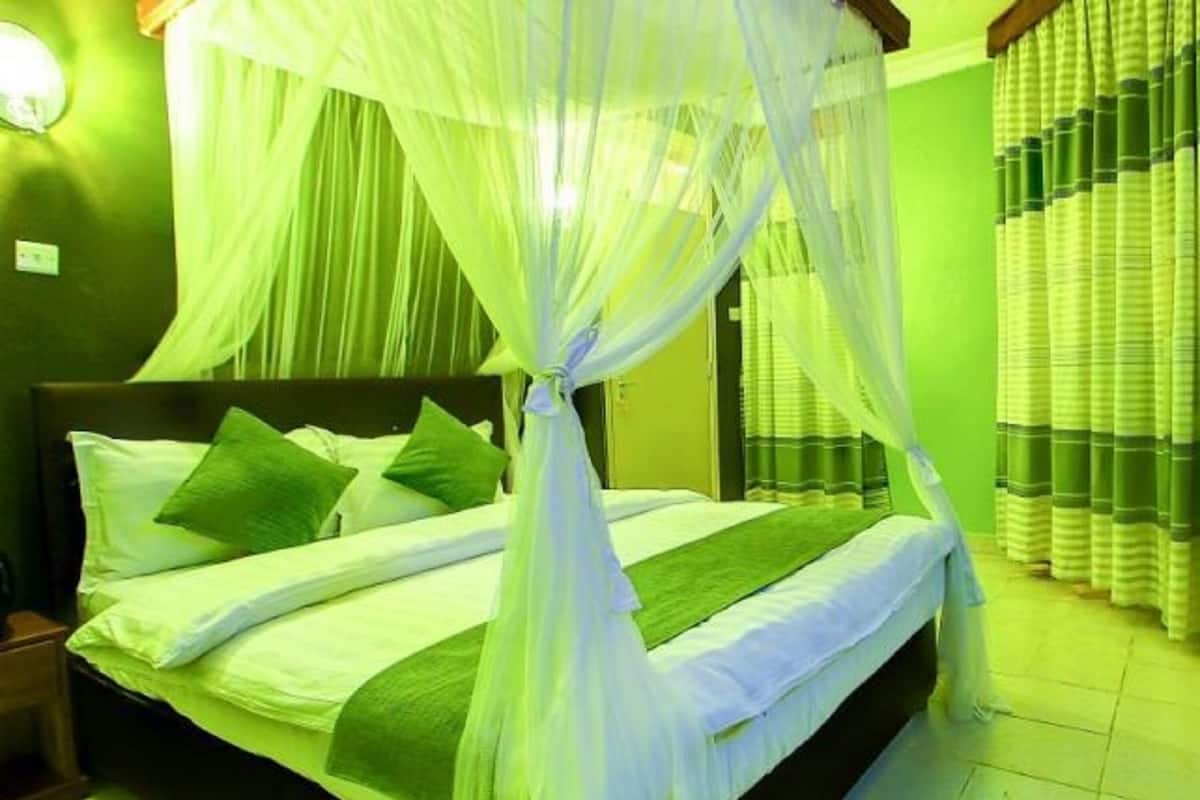 A bed with a canopy, green pillows, and a green bedspread.