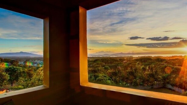 A room with two windows overlooking a landscape with mountains and a sunset. - Olive Resort (Naivasha)