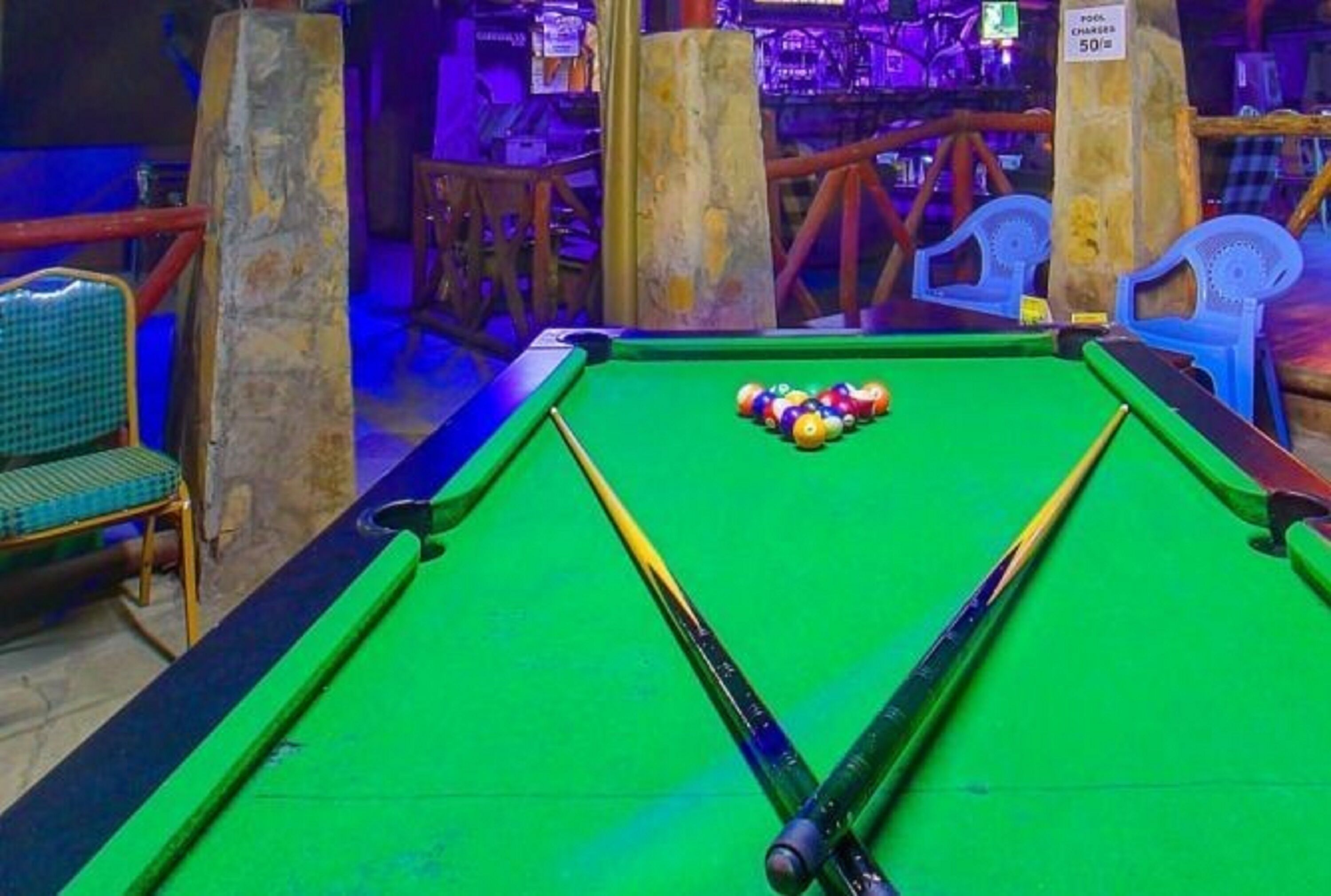 Une table de billard avec des billes, une queue et une chaise.