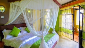 A bed with a canopy, green pillows, and a bedside table. - Olive Resort (Naivasha)