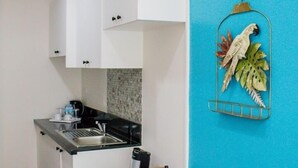 Uma cozinha compacta com armários brancos, bancada preta e uma mesa de jantar de madeira com cadeiras.