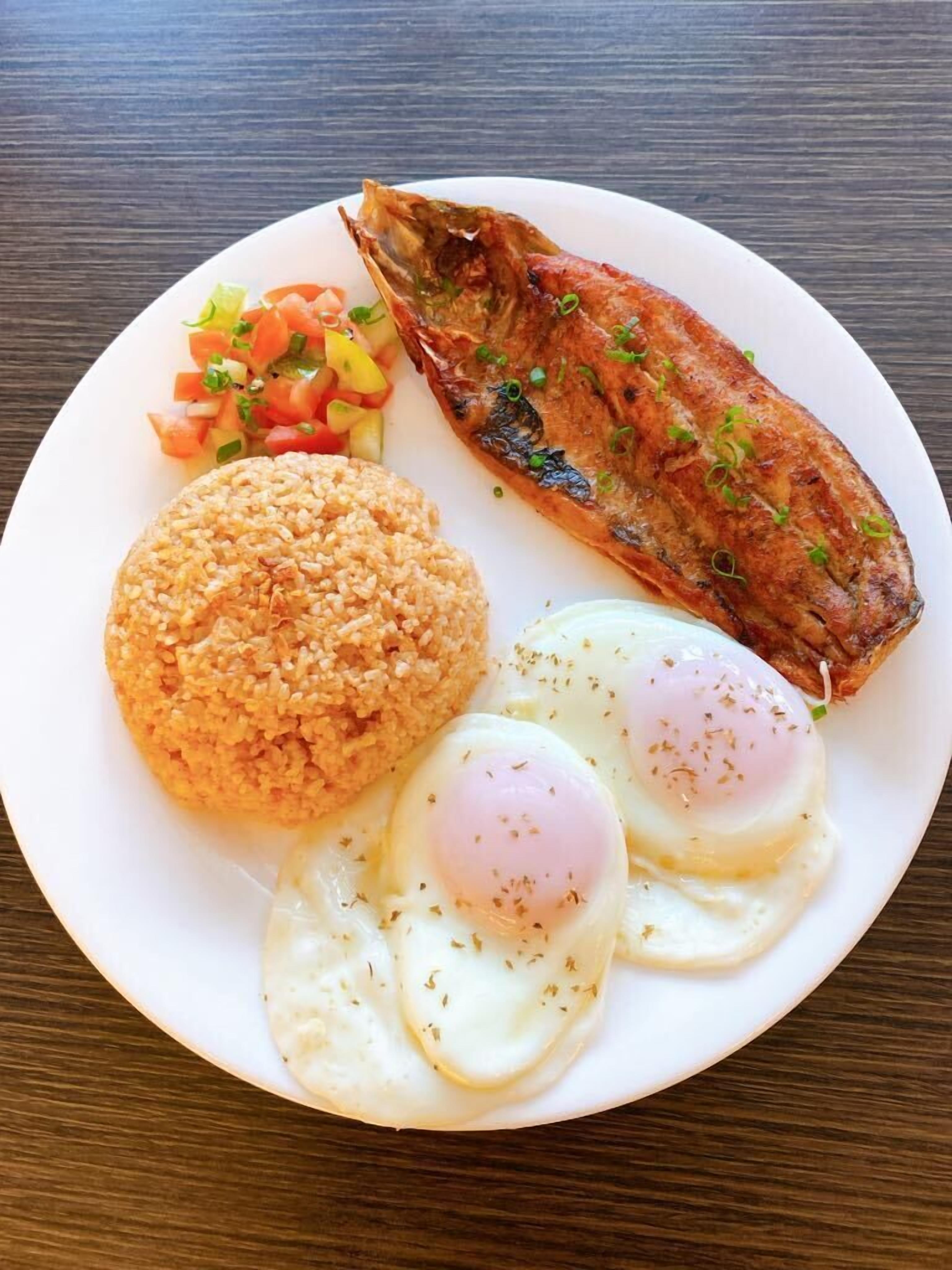 A plate with grilled fish, fried rice, and fried eggs.