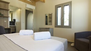 Une chambre avec un grand lit, une commode, une chaise et une fenêtre.