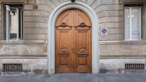 Une grande porte à deux battants, en bois sculpté, ornée de motifs, avec une pancarte indiquant qu’il est interdit de se garer.