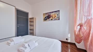 Una habitación de hotel con una cama, un armario, un cuadro en la pared y una cortina.