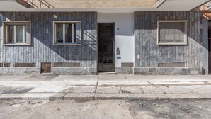 Ein modernes Gebäude mit einer steinernen Fassade, einem zentralen Eingang und einem Balkon im oberen Geschoss.
