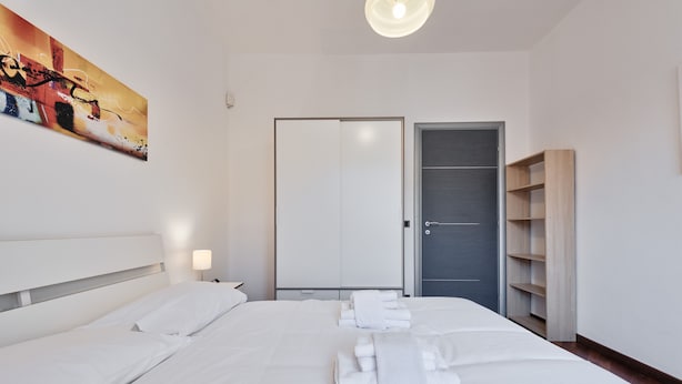Ein Hotelzimmer mit einem großen Bett, einem Kleiderschrank und einem Gemälde an der Wand.
