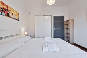A hotel room with a large bed, a wardrobe, and a painting on the wall. - Vanchiglietta Colourful Apartment (Turin)