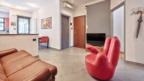 Ein modernes Wohnzimmer mit einem roten Sessel, einem braunen Sofa und einem Flachbildfernseher.