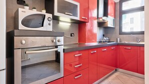 Eine moderne Küche mit roten Schränken, einer eingebauten Mikrowelle, einem Backofen und einem Gasherd.
