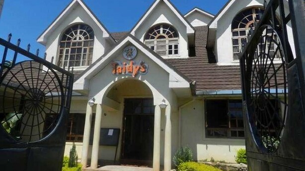 A building with a distinctive arched entrance and a sign that reads "Taidy's." - Taidys Suites Kericho (Kericho)
