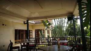 An outdoor patio area with tables and chairs, surrounded by a railing, and featuring large windows and doors. - Taidys Suites Kericho (Kericho)