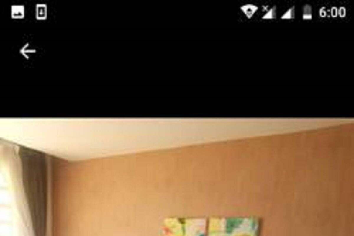 Una habitación de hotel con una cama, almohadas, una mesita de noche y una pared decorada con obras de arte.
