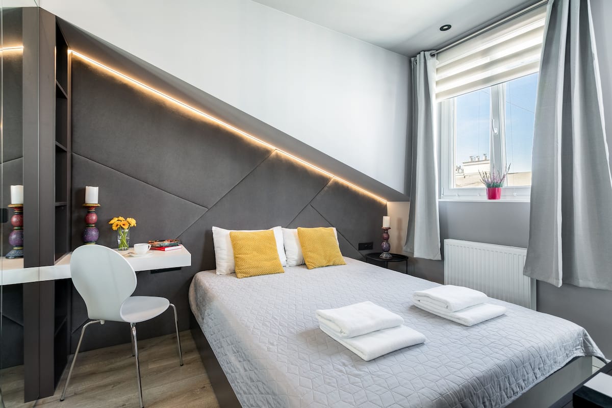 A modern bedroom with a bed, a desk, and a chair.