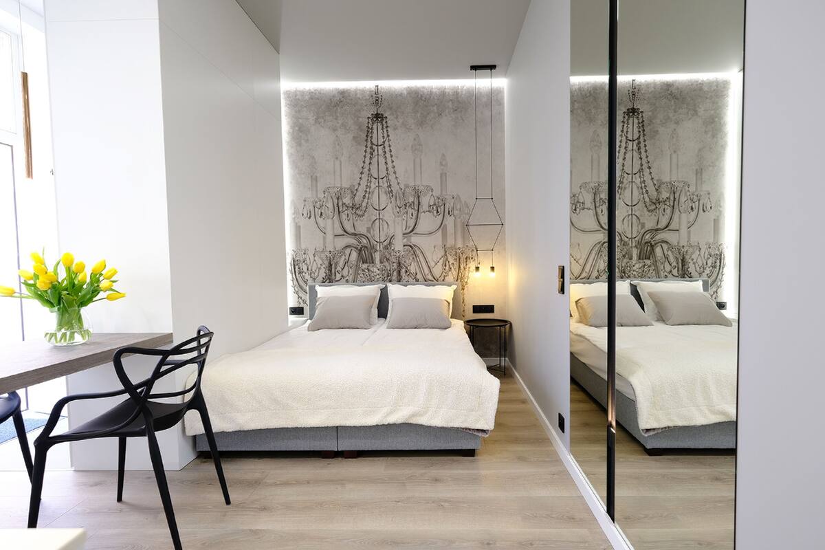 A modern bedroom with a large bed, bedside tables, a desk, and a chair.