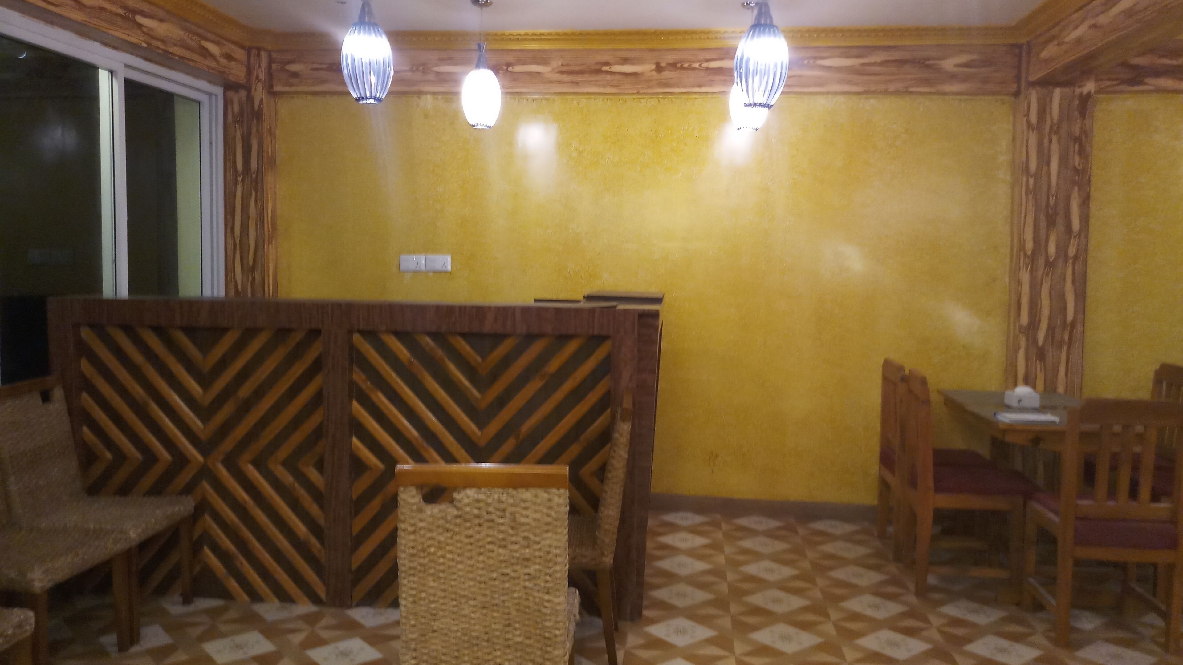 Un comedor con un separador de madera, una mesa con sillas y un suelo estampado.