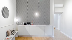 Una cocina moderna con encimera blanca, pared con diseño y aire acondicionado integrado.