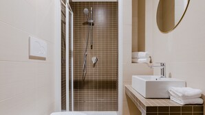 Un baño moderno con ducha, inodoro, lavabo y espejo.