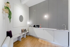 A modern kitchen with white cabinetry, a checkered wall, and a bench with cushions. - Suites by Chloe (Rome)