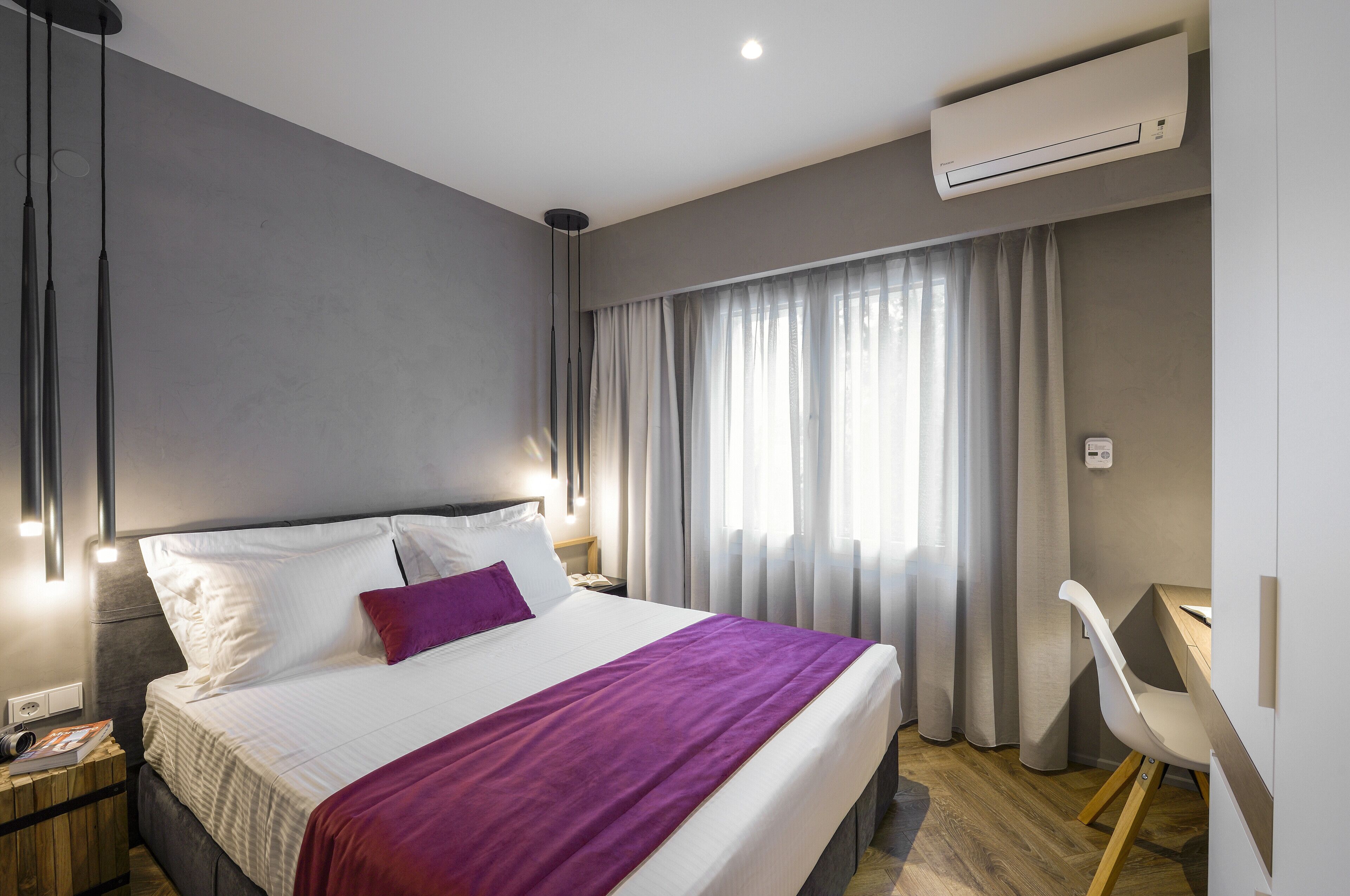 A modern hotel room with a large bed, a desk, and a chair.